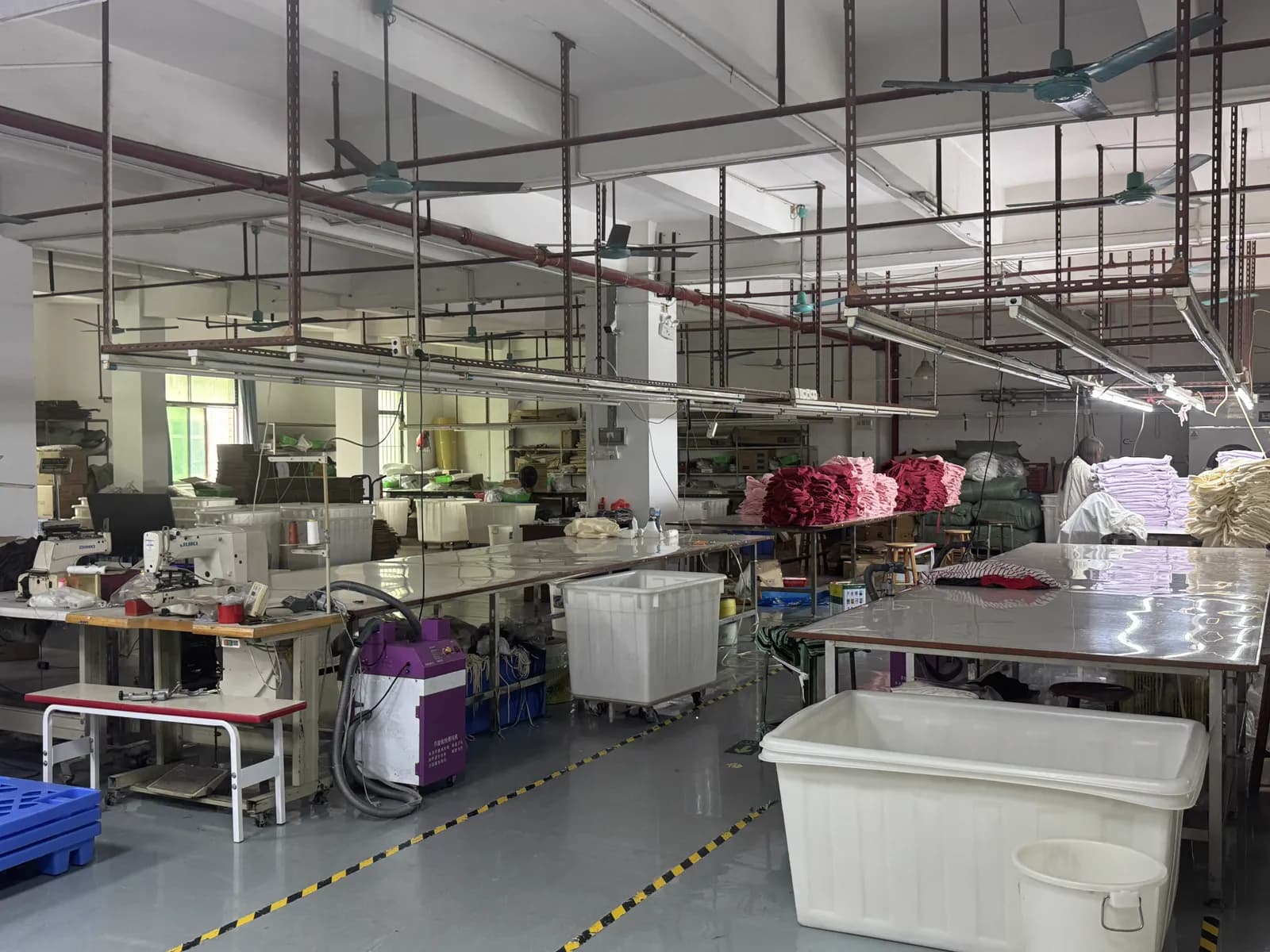 Production floor with sewing machines and a worker at Pindon's Dongguan clothing factory
