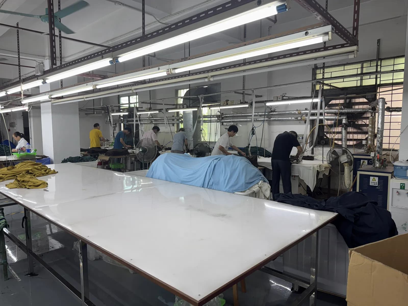 Workers pressing garments at finishing stations in Pindon's Dongguan factory
