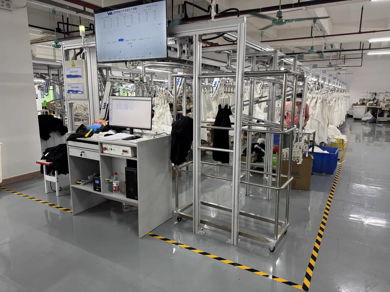Worker at a hanging production rail and station monitor in Pindon's factory