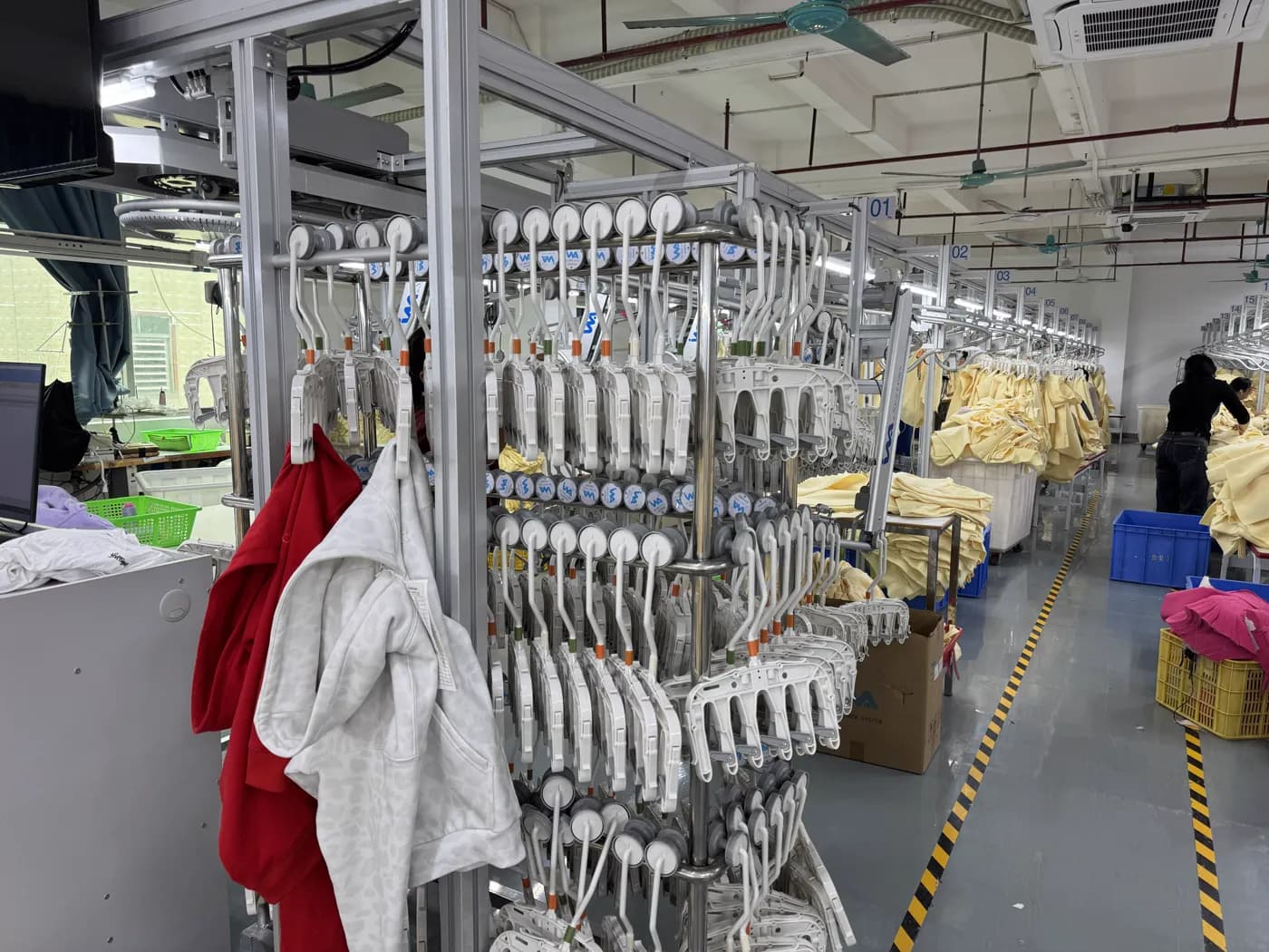 Hoodies hanging on the production rail with a worker at a numbered station
