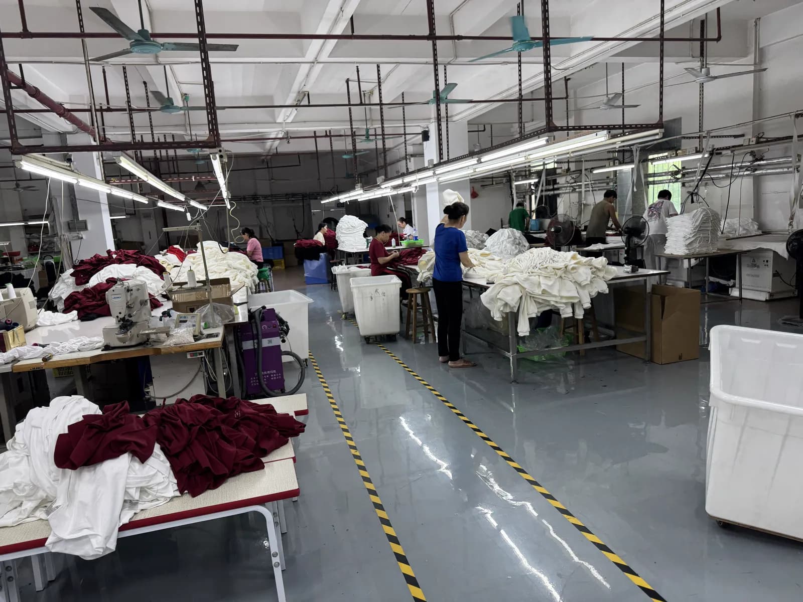 Workers sewing white and maroon garments on the production floor at Pindon's Dongguan factory