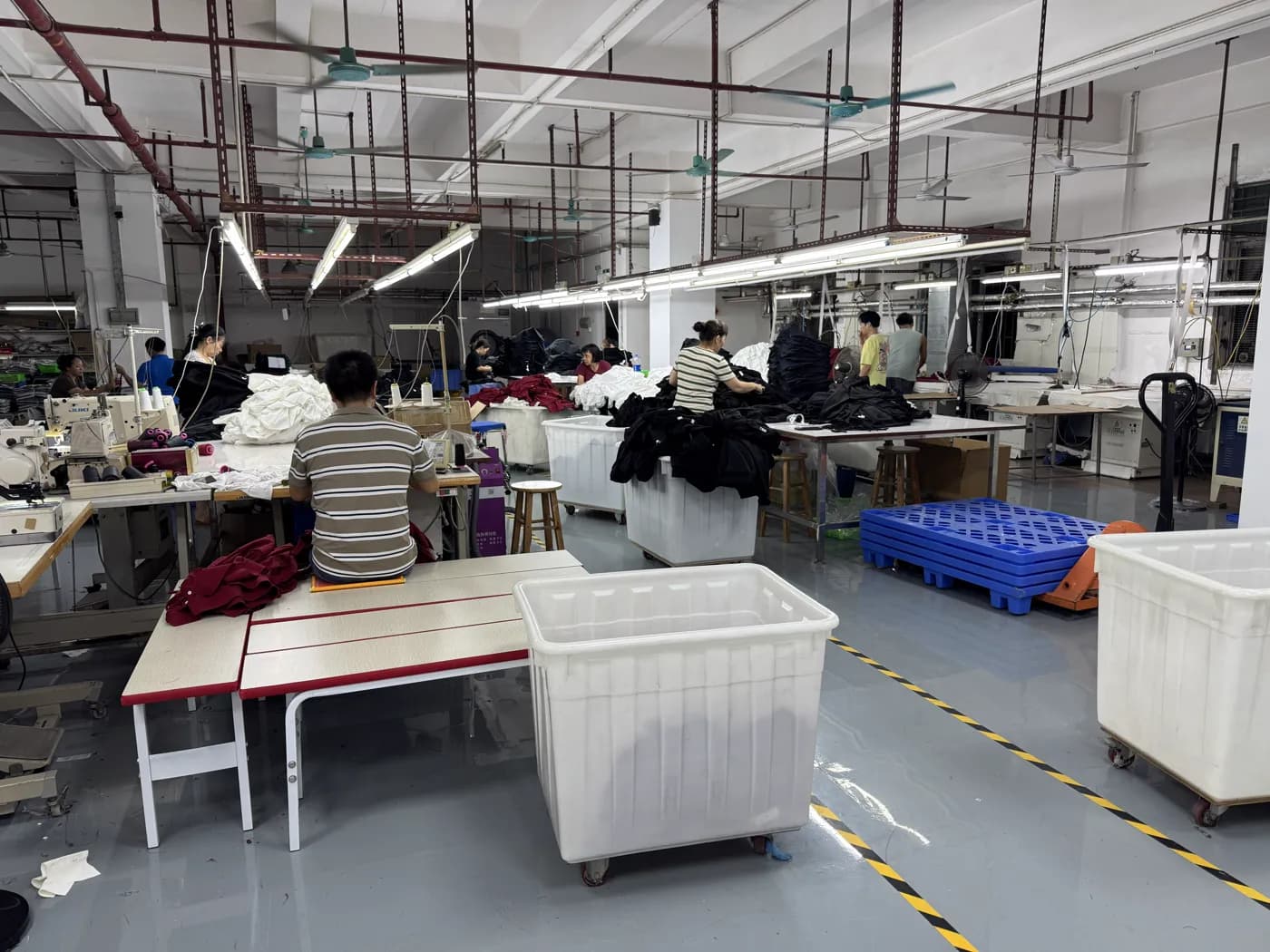 Workers sewing and sorting garments on the factory floor in Dongguan