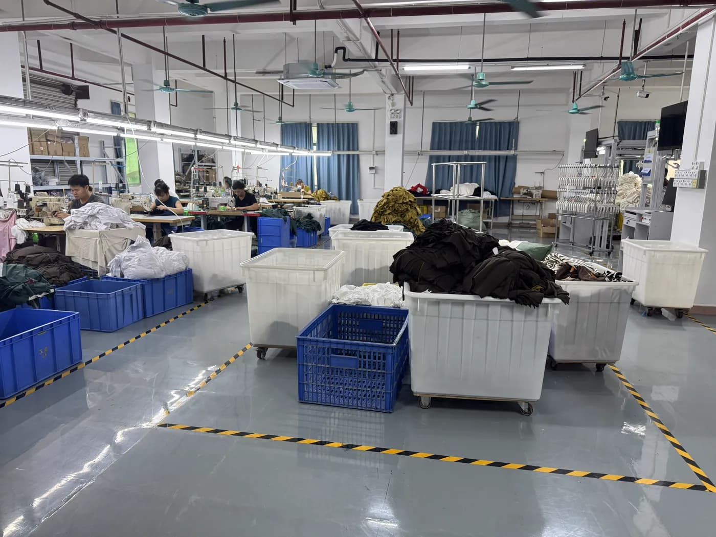 Sewing stations with hanging white garments at Pindon's Dongguan factory