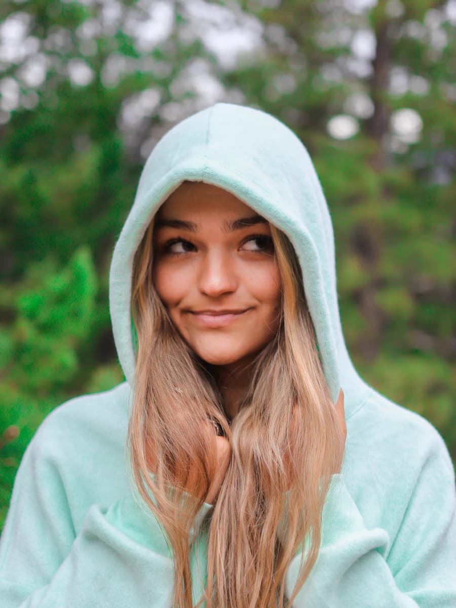 Adult model style reference — woman in white hoodie standing near green trees during daytime